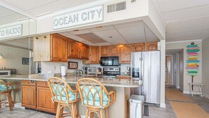 Una cocina moderna con armarios de madera, una isla central con taburetes de bar, un refrigerador y un microondas.