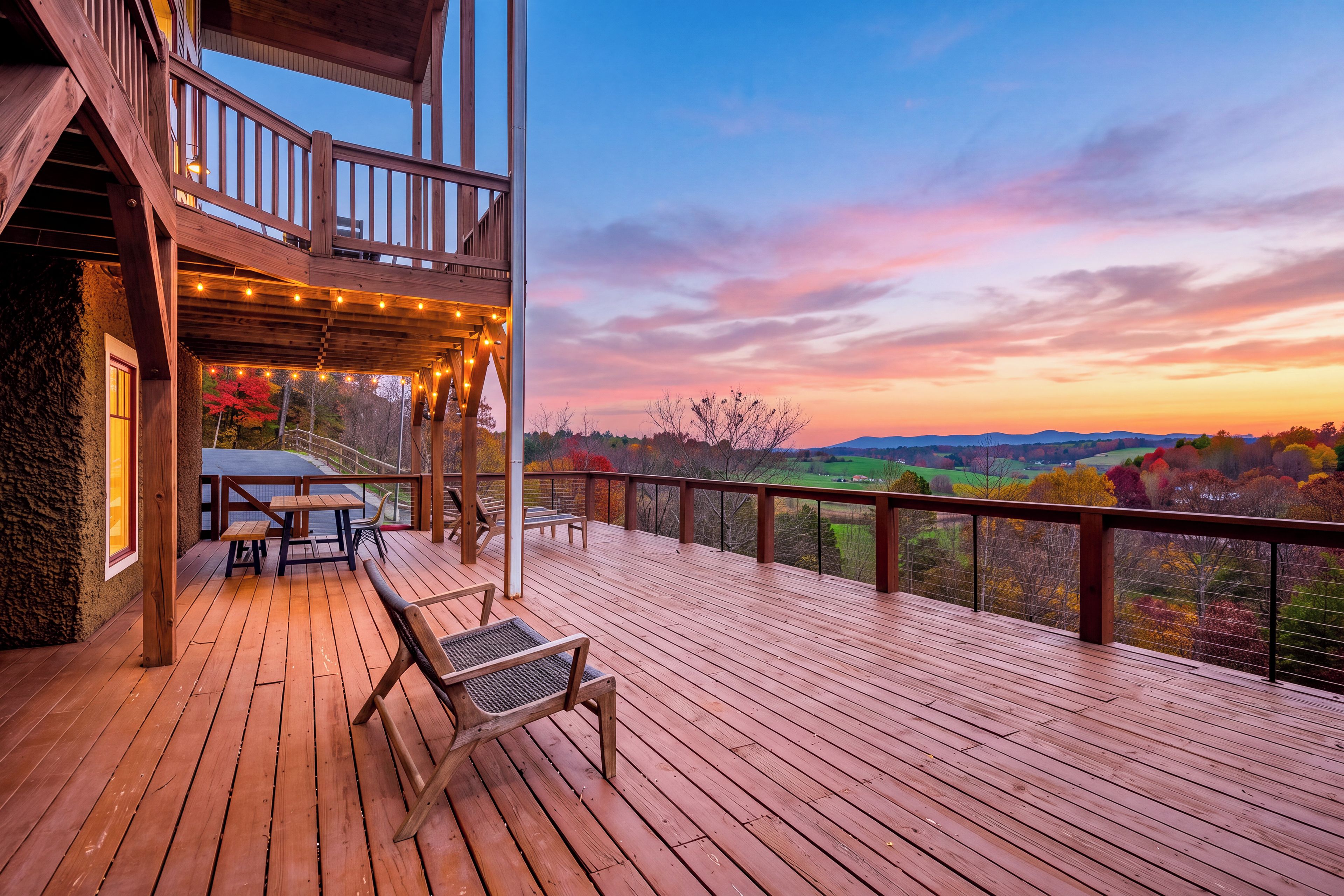 Une terrasse en bois avec des sièges extérieurs et une vue sur un paysage au coucher du soleil.