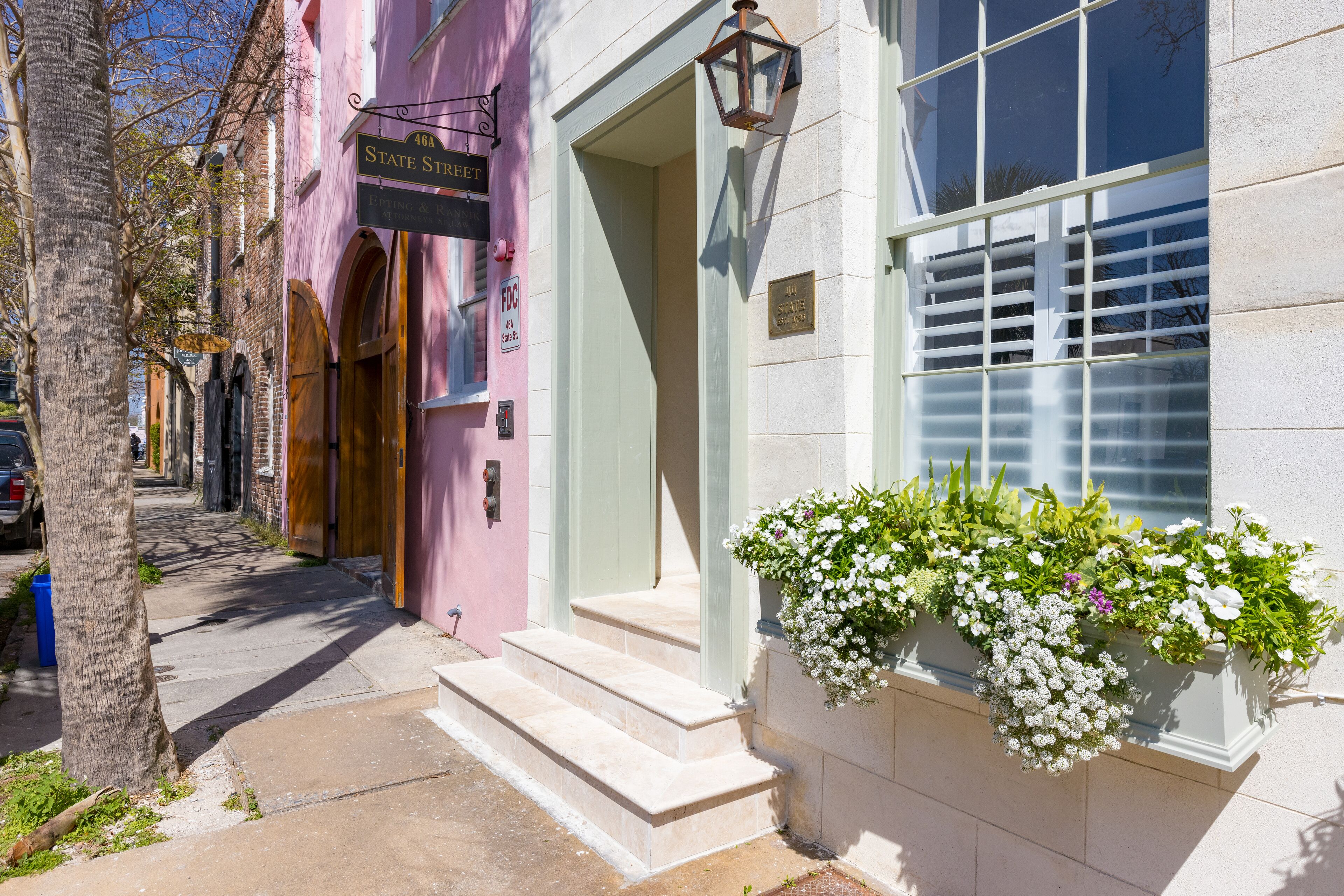 A building with a pink facade, a sign reading "State Street," and a window with white flowers.