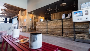 Un interior de madera con una recepción, un banco rojo y una mesa blanca con una taza y un menú.