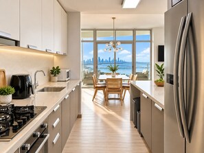 Une cuisine moderne offrant une vue sur les gratte-ciel de la ville grâce à de grandes fenêtres.
