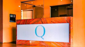 Un mostrador de recepción con diseño de mármol y un gran letrero iluminado con la letra 'Q'.