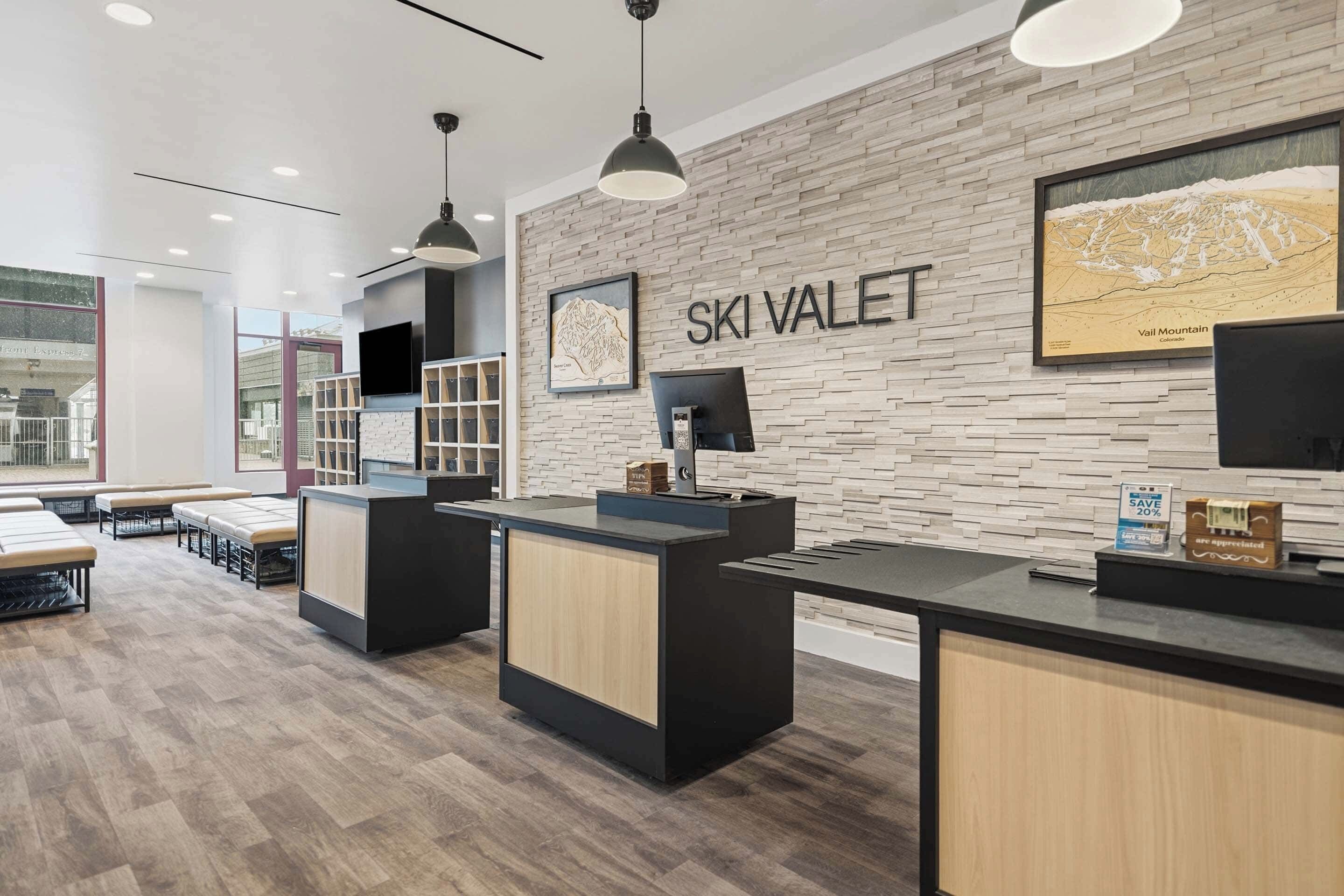 A modern reception area with a wooden wall, a mounted TV, and a sign that reads 'SKI VALET'.