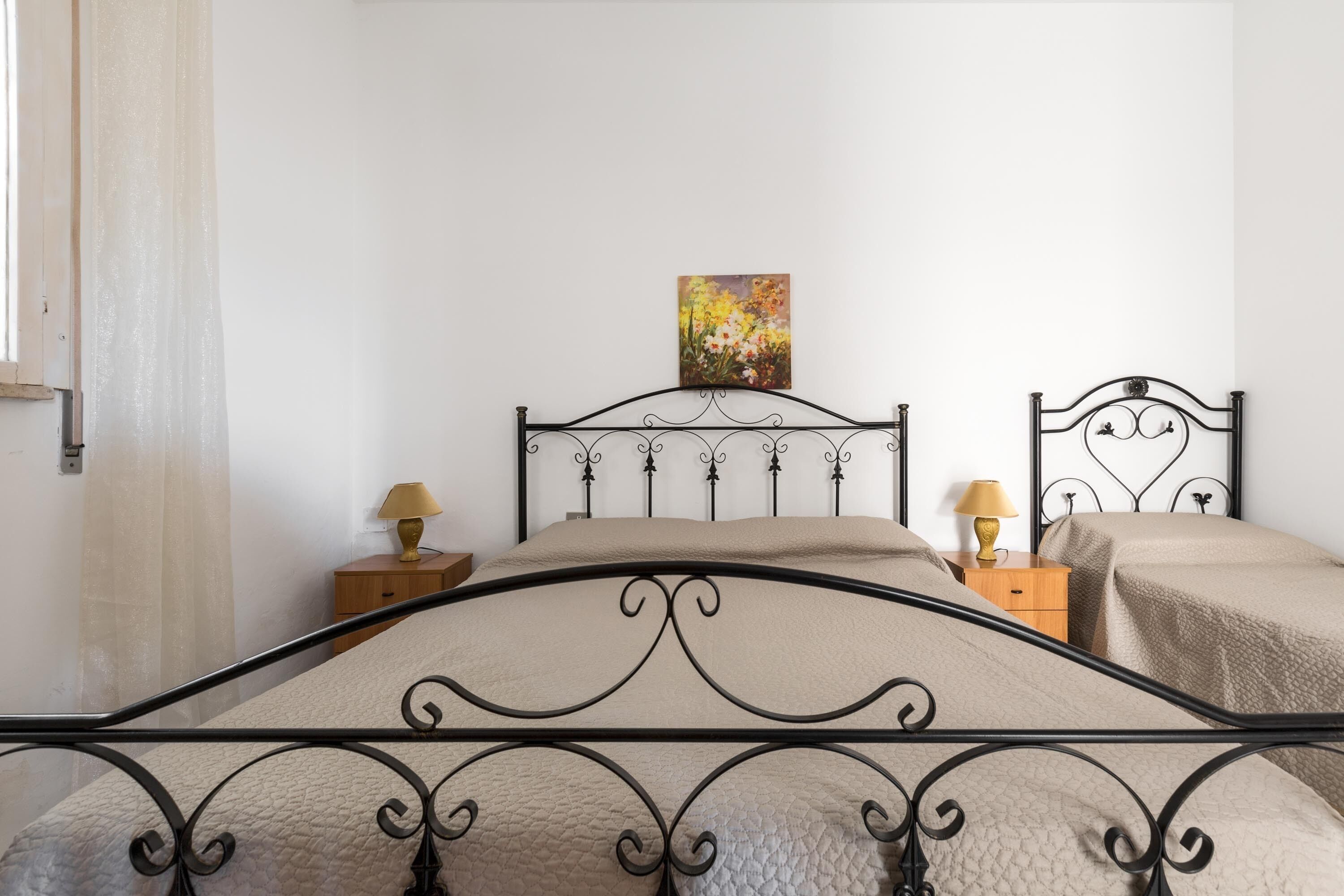 A neatly arranged bedroom with a bed, two bedside tables, and a painting on the wall.