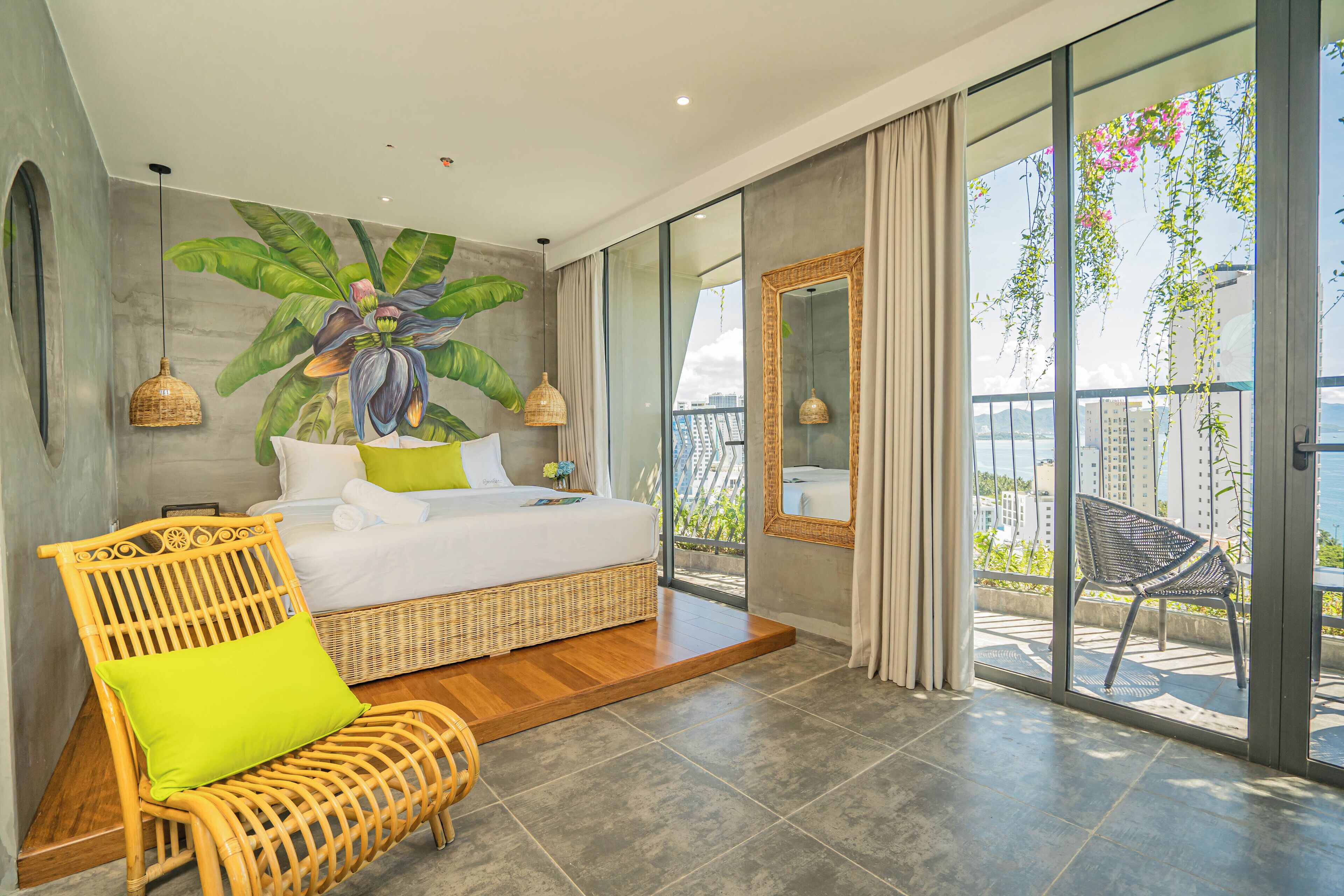 A modern bedroom with a large bed, a wicker chair, and a view of the balcony.
