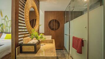 A modern bathroom with a large mirror, a wooden cabinet, a sink, and a glass shower enclosure.