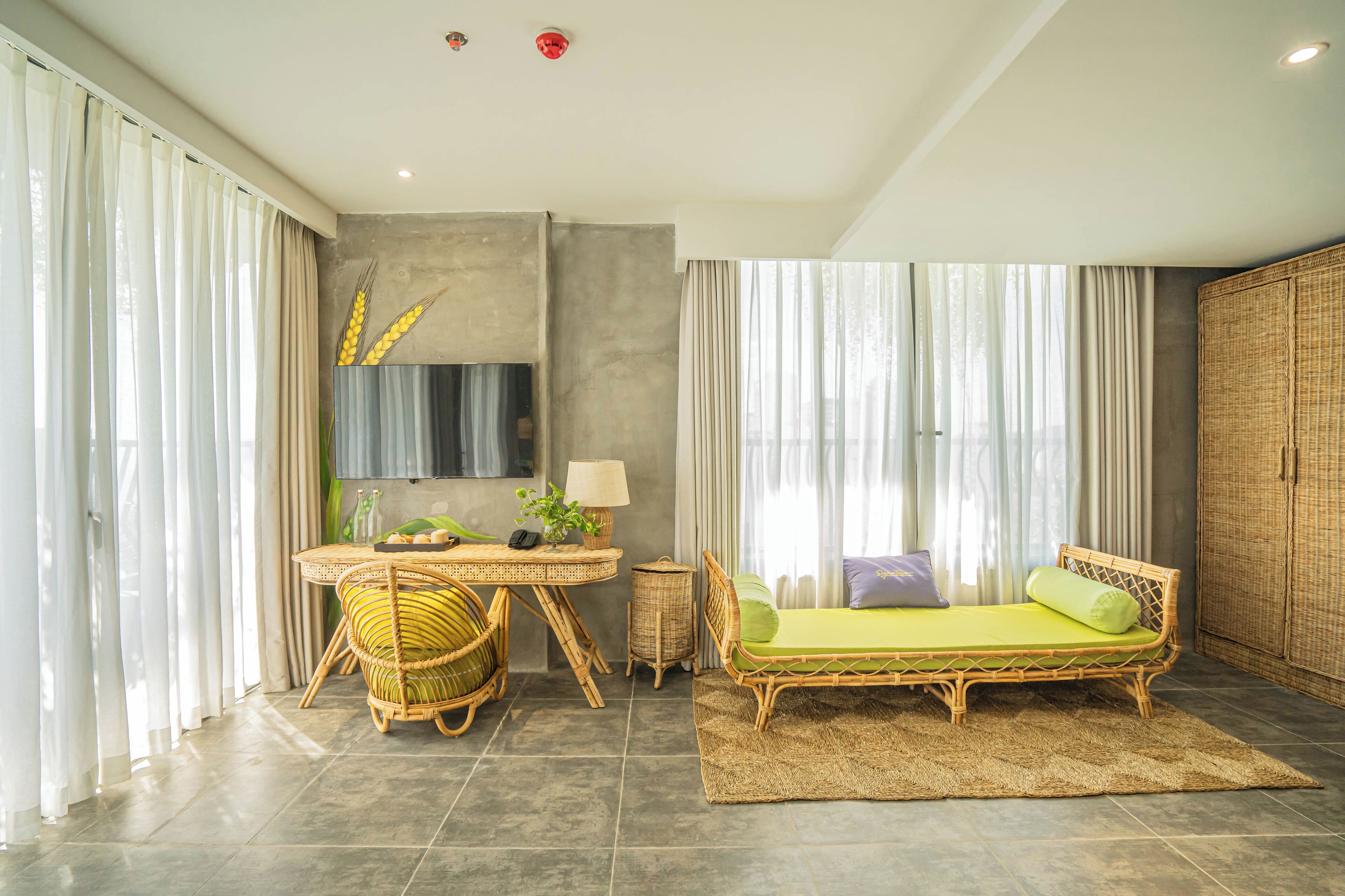 A modern room with a bed, a desk, and a wicker chair.