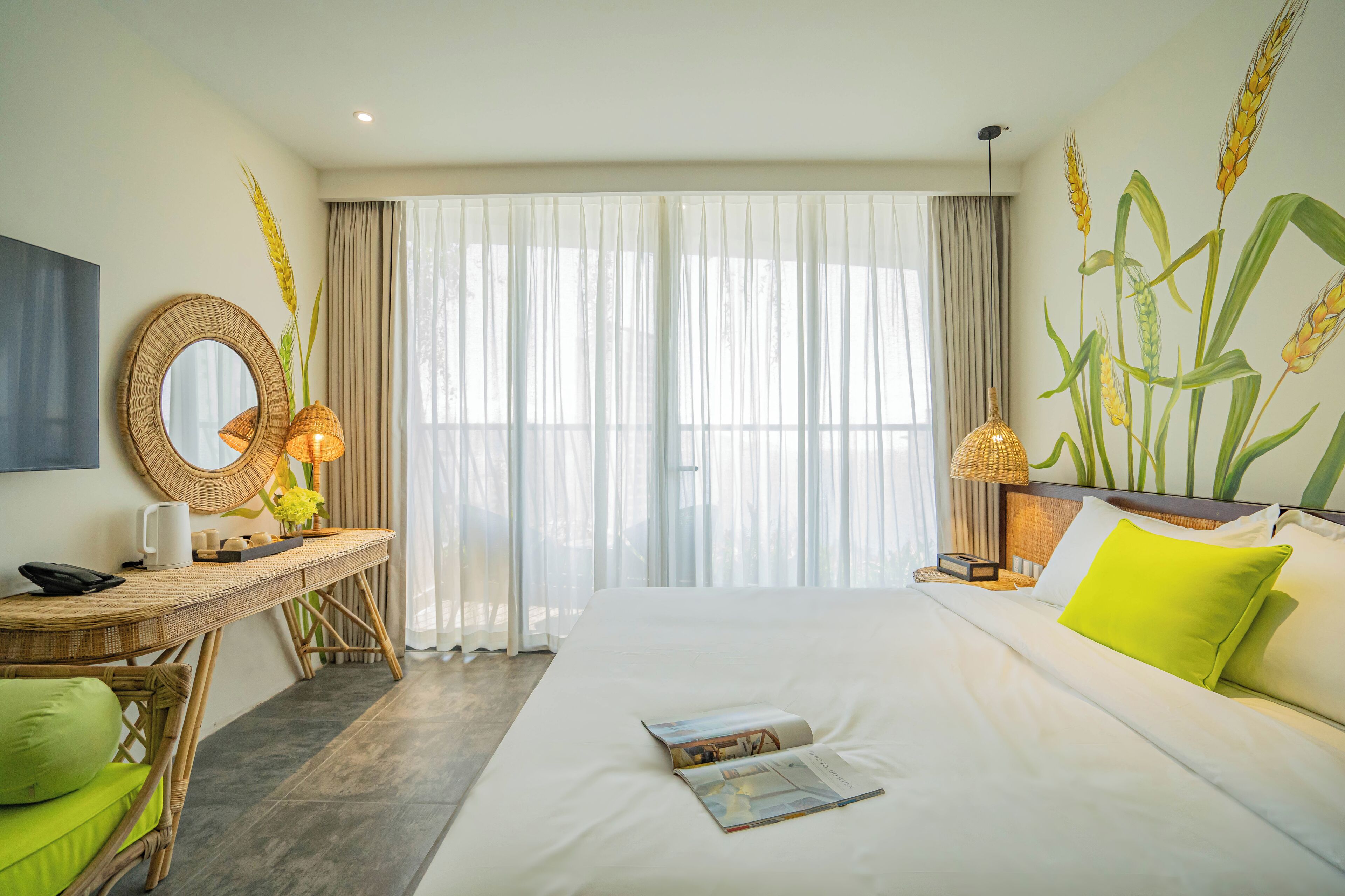 A hotel room with a bed, a desk, a chair, a mirror, and a window with curtains.