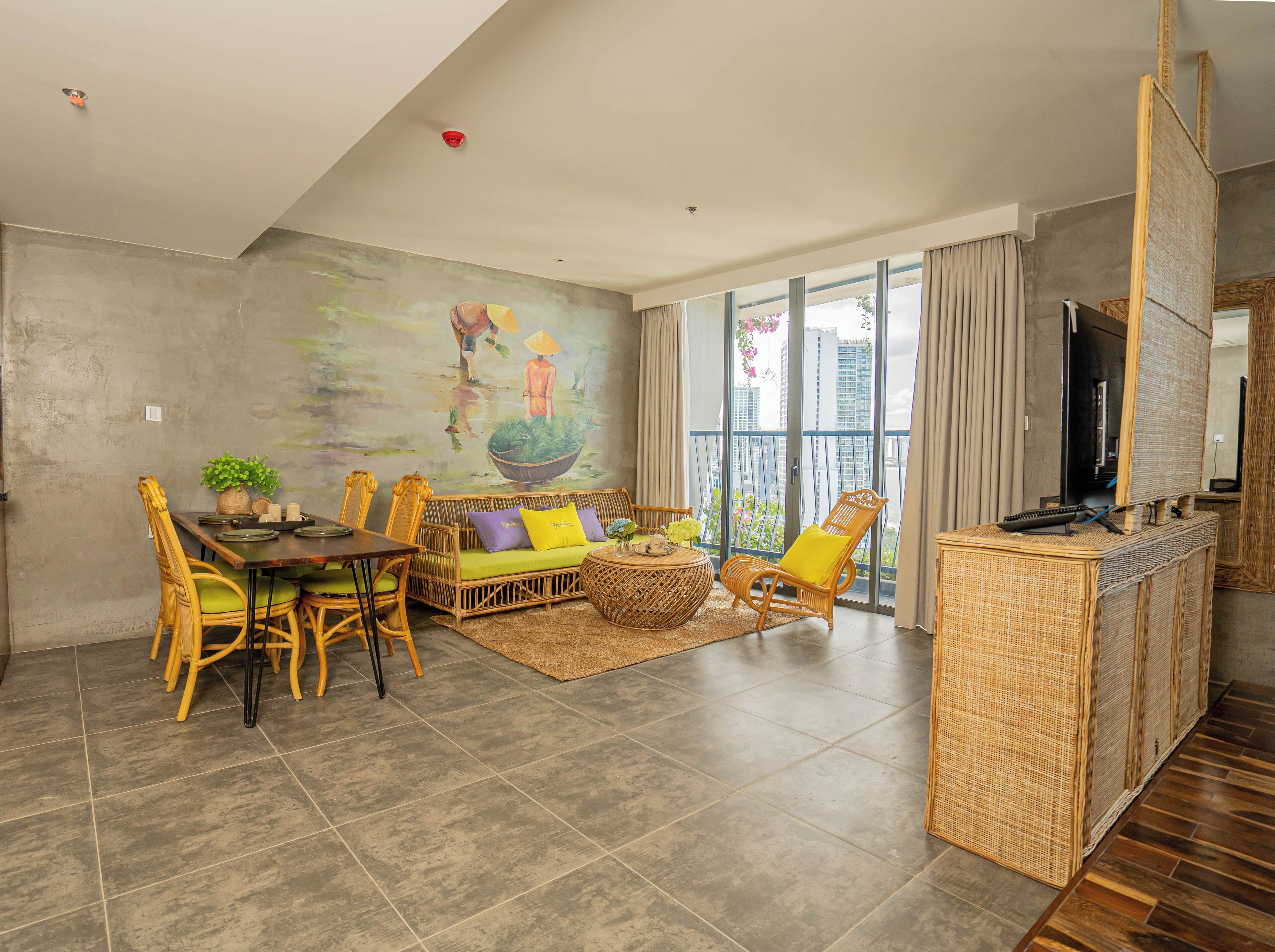 A modern living room with a dining area, a large window with a view of buildings, and a flat-screen TV on a stand.