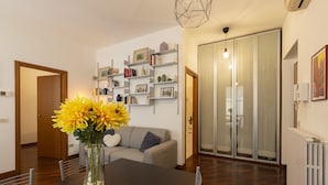 Een moderne woonkamer met een eettafel, bank en inbouwplanken met boeken en decoratieve objecten.