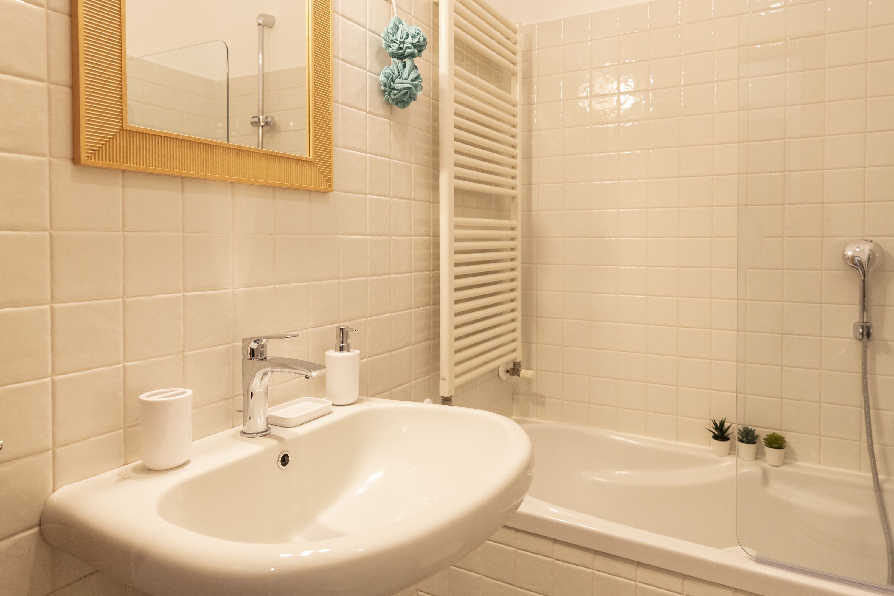 A bathroom with a sink, mirror, and bathtub.