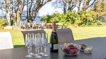 A table set outdoors with a bottle of Moët & Chandon champagne, several glasses, a bowl of fruit, and a bowl of nuts.