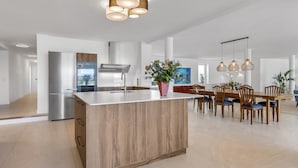 Una cocina moderna con una isla central, electrodomésticos de acero inoxidable e iluminación colgante.