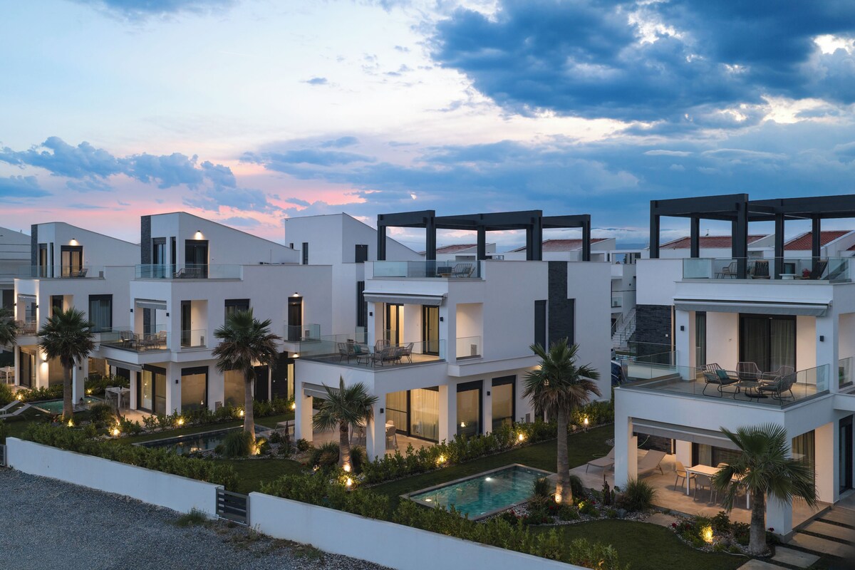 A modern multi-story hotel with balconies, a swimming pool, and outdoor seating areas.