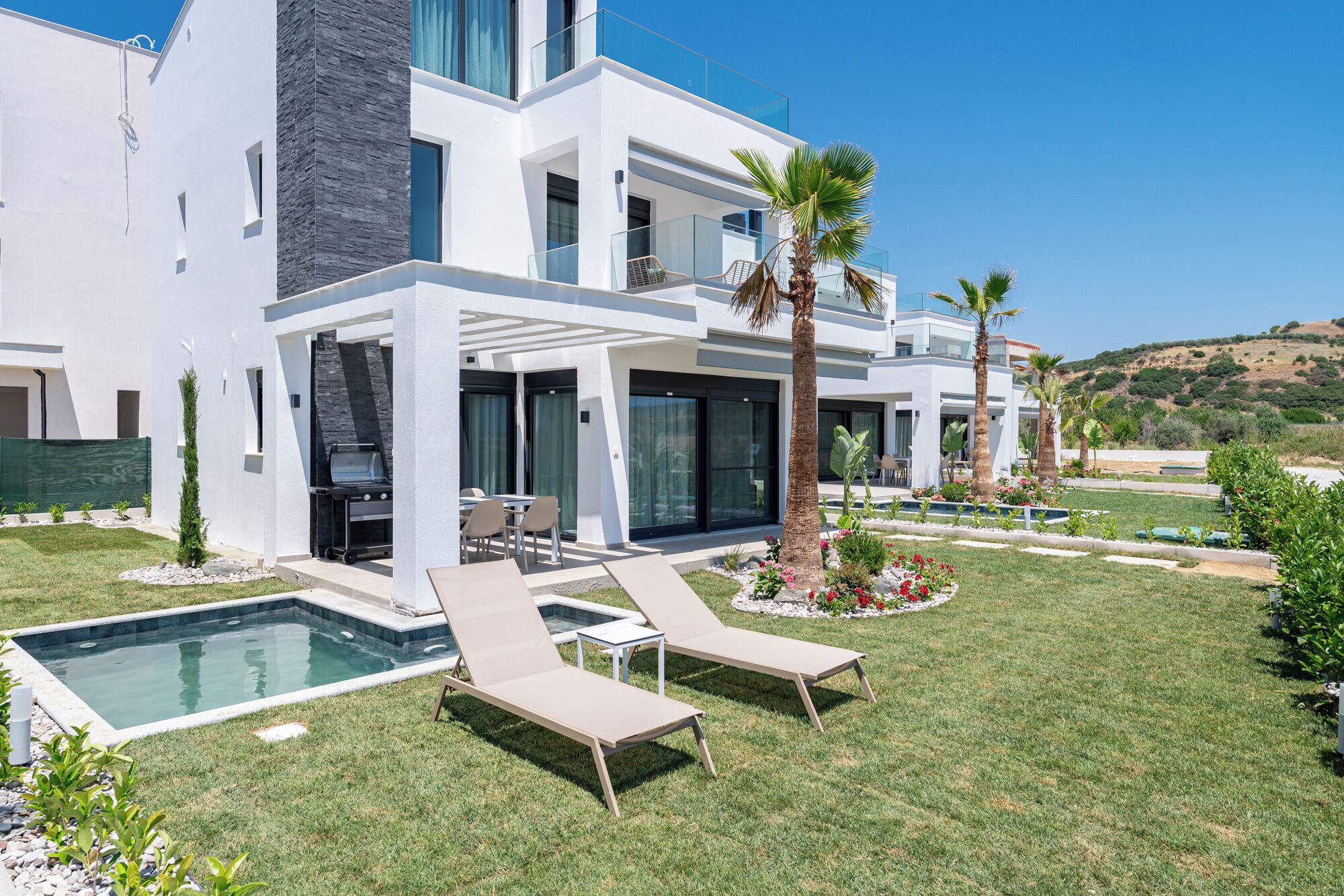 A modern two-story house with a swimming pool, outdoor seating, and a well-maintained garden.