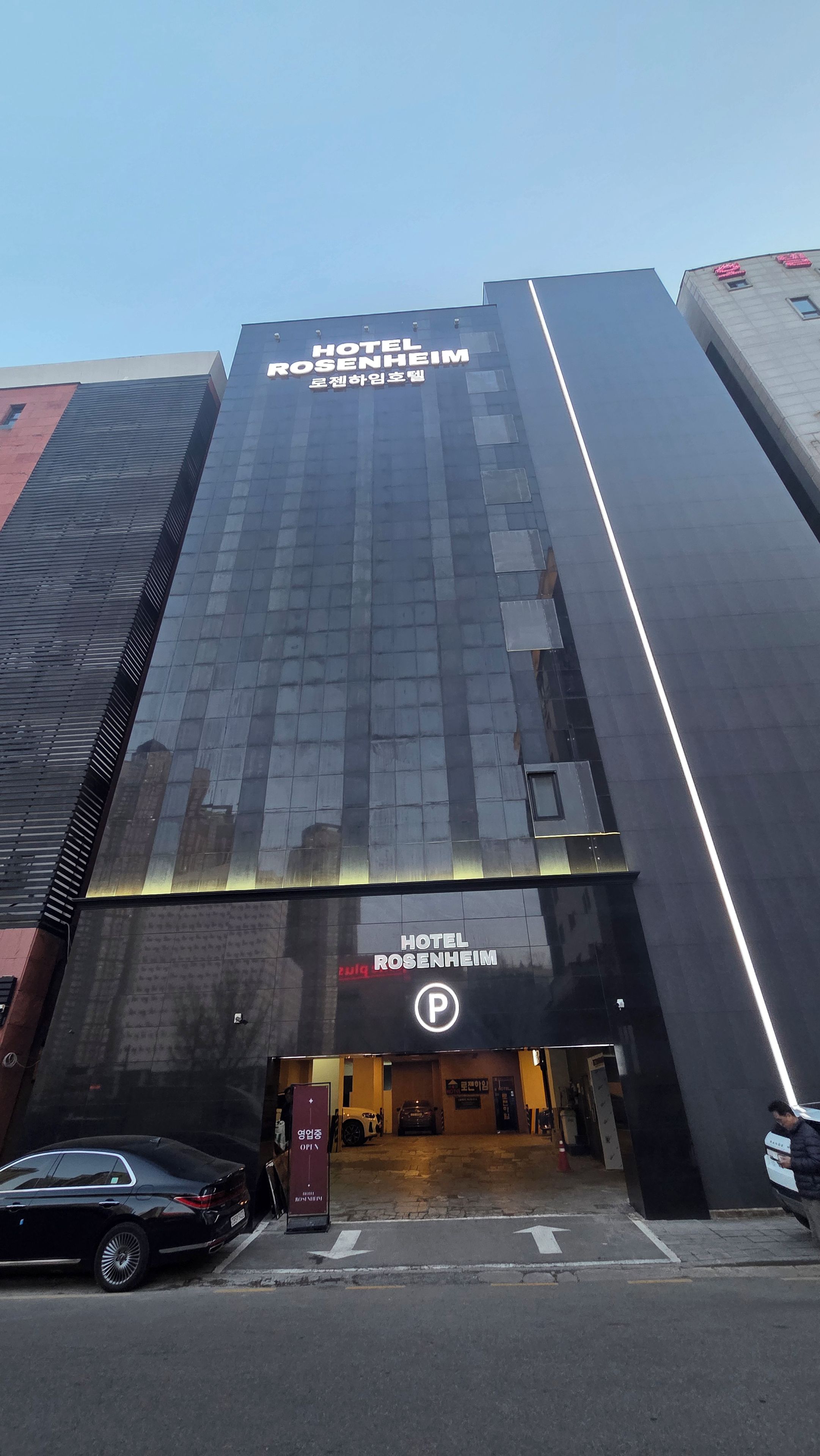 A modern hotel building with a prominent entrance and a parking sign.
