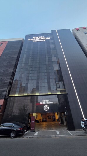 Un moderno edificio de hotel con una entrada destacada y un letrero de estacionamiento.