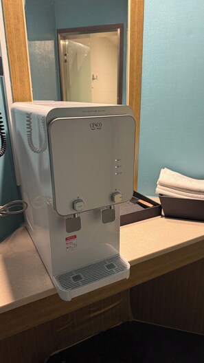 Un dispensador de agua con un botón pulsador, un panel de control con una perilla y una etiqueta en un idioma extranjero.