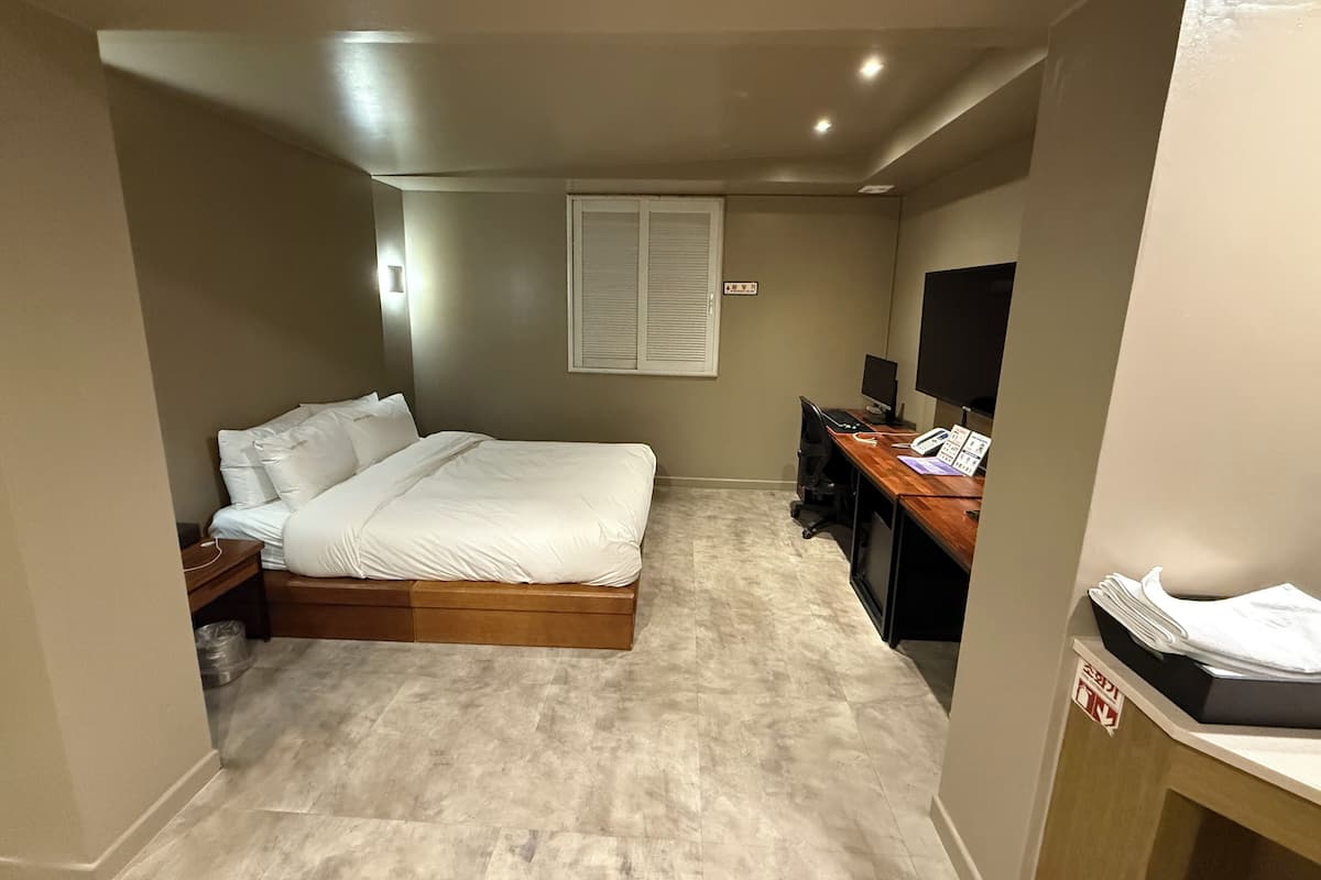 Un dormitorio con una cama, un escritorio con computadora y una televisión.