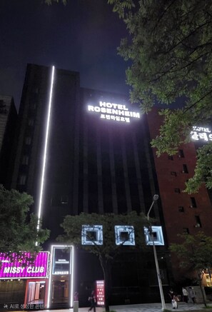 A hotel with a prominent sign, surrounded by trees and other buildings. - ROSENHEIM (Goyang)