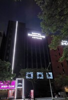 Un hotel con un letrero llamativo, rodeado de árboles y otros edificios.