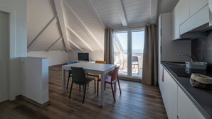 A modern kitchen with a dining area, large windows, and a view of the outdoors. - Villa Cadiz Apartments Varazze (Varazze)