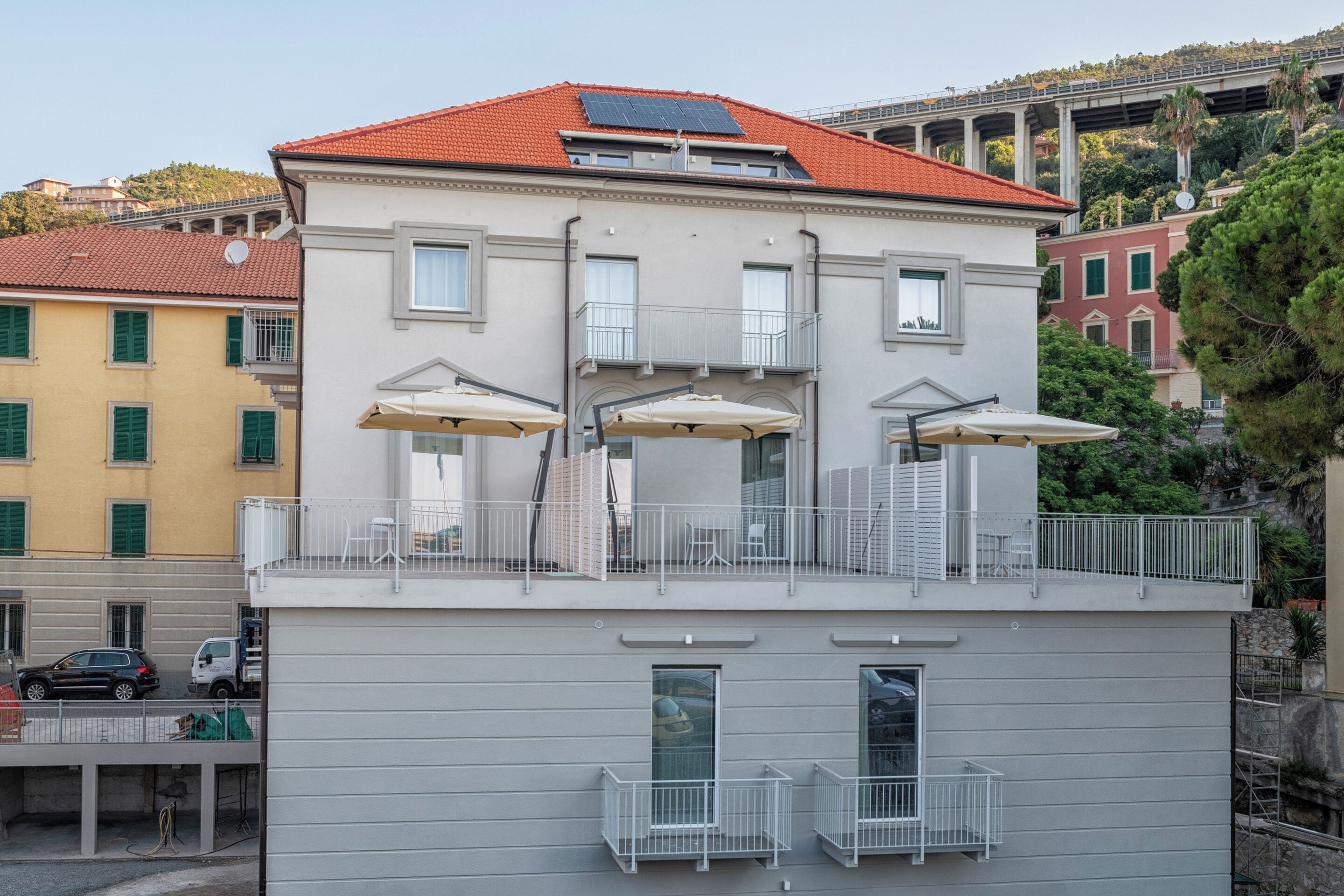 Un edificio a più piani con balconi, area salotto esterna e tetto in tegole rosse.