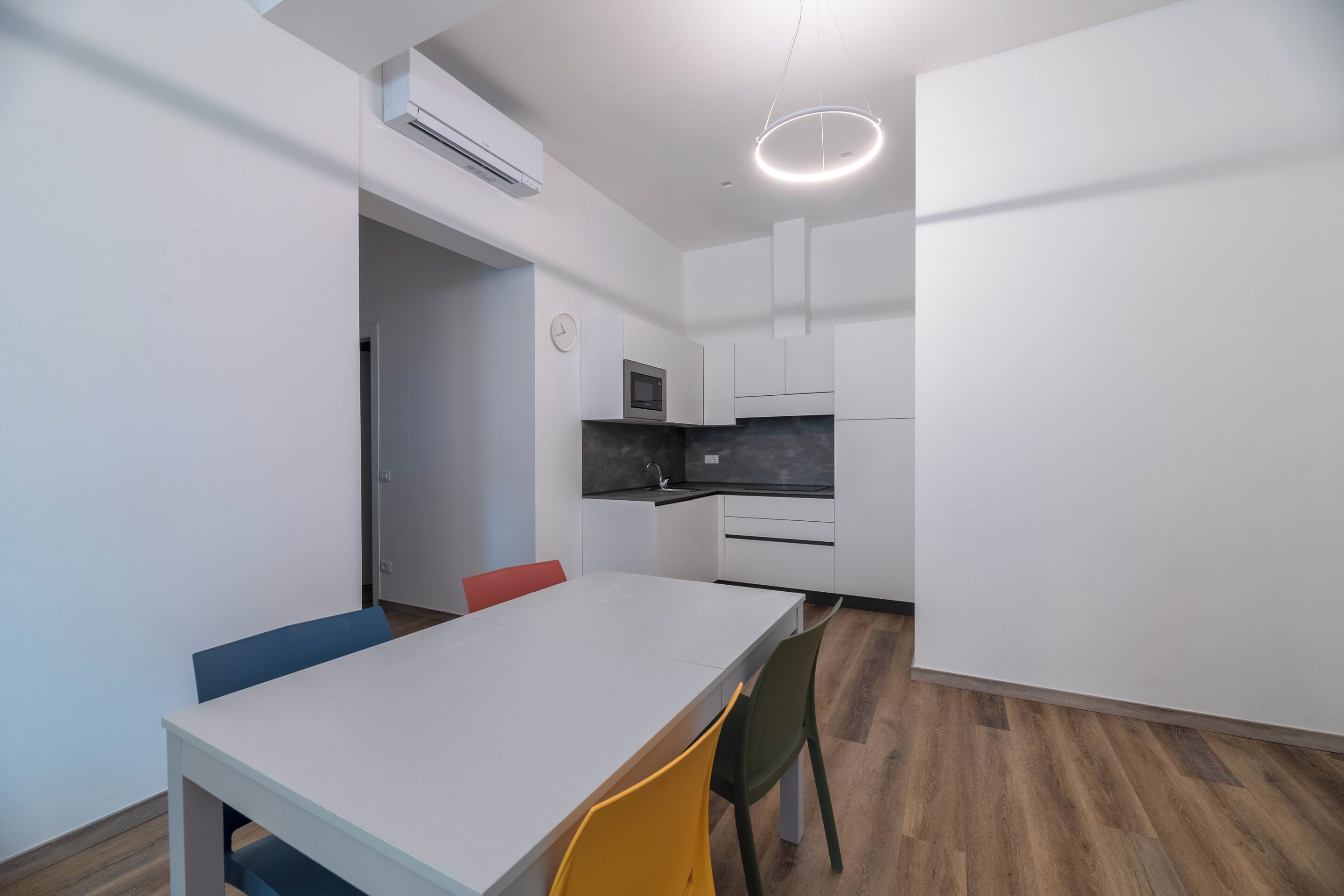 Una cucina moderna con mobili bianchi, un piano di lavoro nero e un forno a microonde integrato.