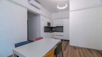 Una cucina moderna con mobili bianchi, un piano di lavoro nero e un forno a microonde integrato.