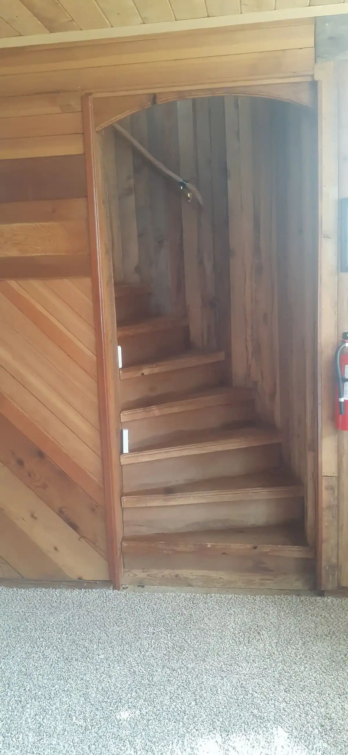 Un escalier en bois mène à une mezzanine située sous un plafond en pente.