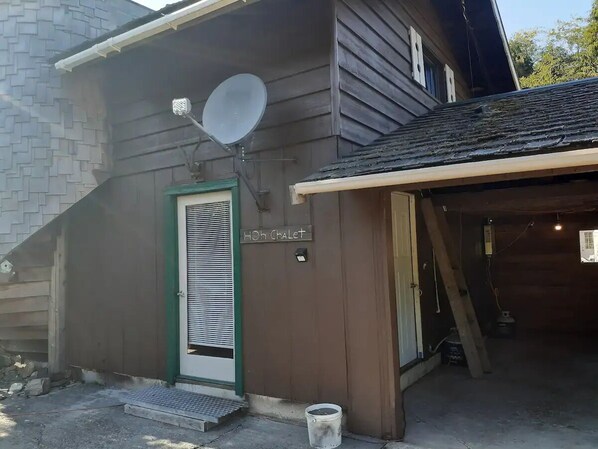 A wooden house with a satellite dish, a green door, and a sign reading "HOH ChaLeT". - Hoh Chalet A cozy cabin on the Olympic Peninsula (Forks)