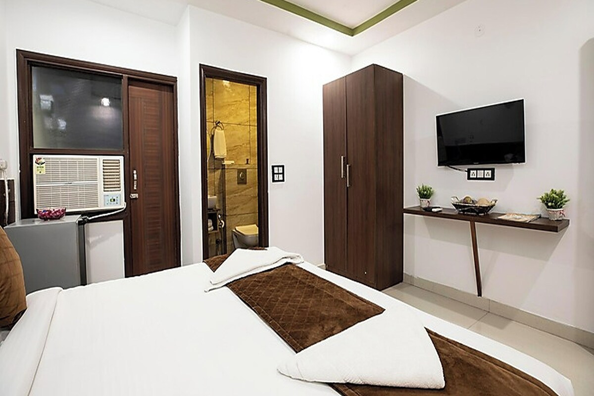 A bedroom with a bed, a TV, a desk, and a wardrobe.