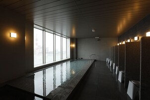 Una piscina interior moderna con paredes de vidrio transparente, un largo banco y una fila de inodoros.
