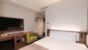 A hotel room with a bed, a TV, a desk with a phone, a chair, and a small table.
