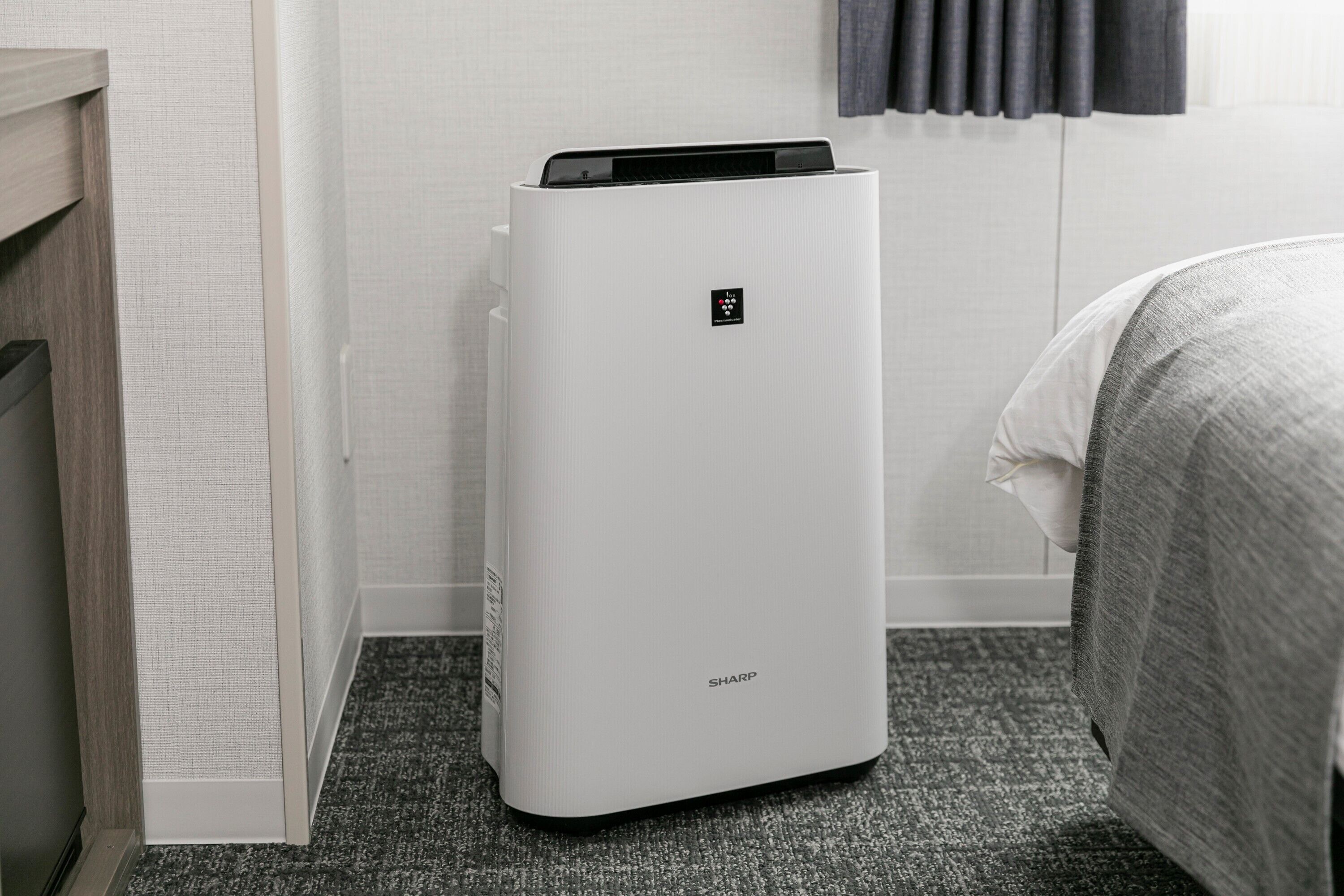 A white air purifier with a control panel in a hotel room.