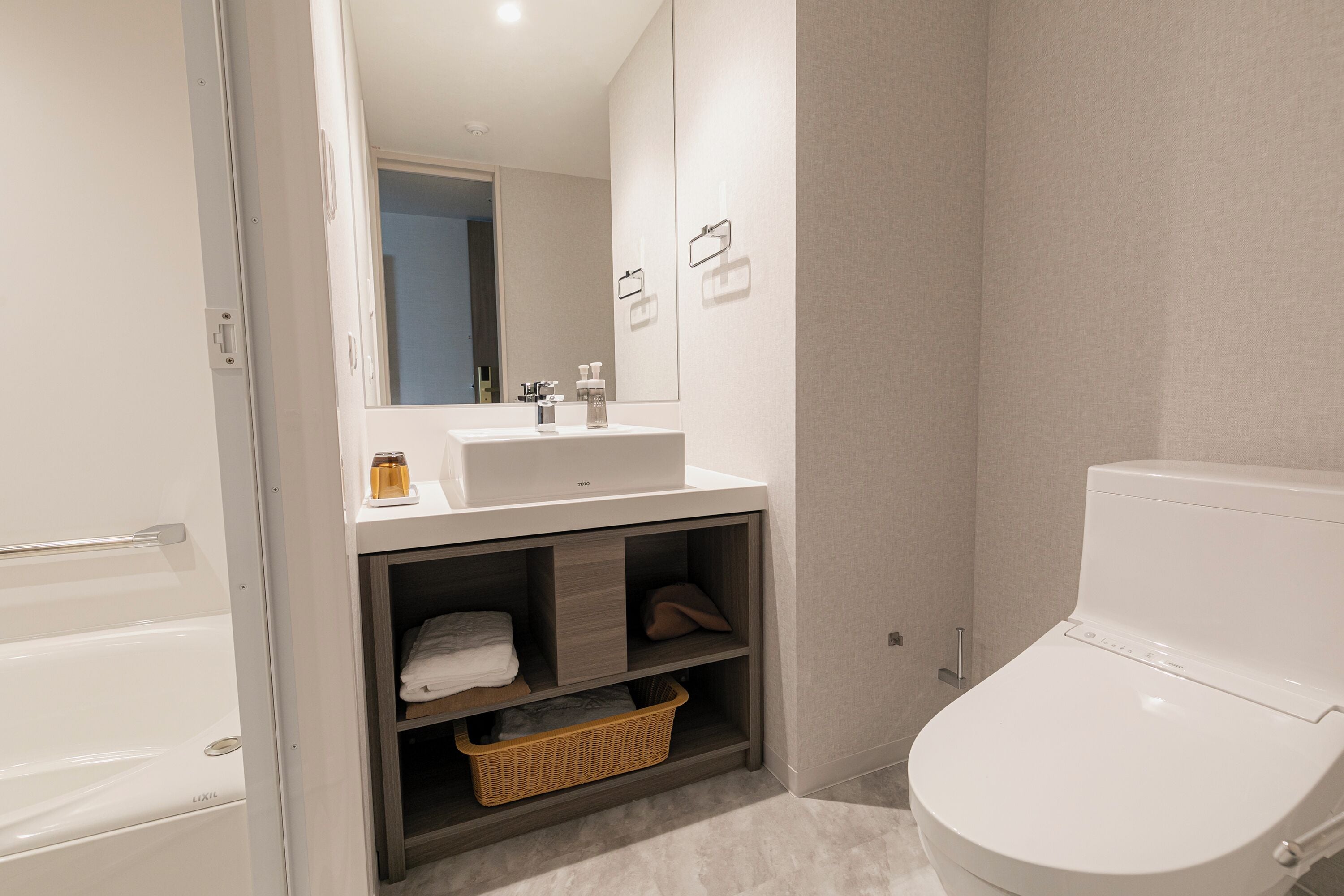A modern bathroom with a white bathtub, a sink with a mirror, and a toilet.