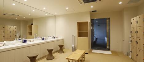 A modern bathroom with a large mirror, multiple sinks, and a bench.