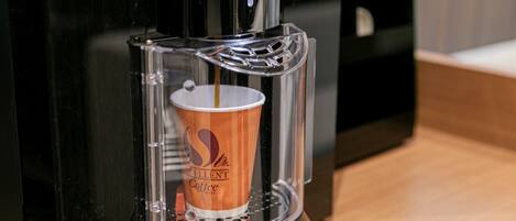 Una cafetera sirviendo café en una taza.