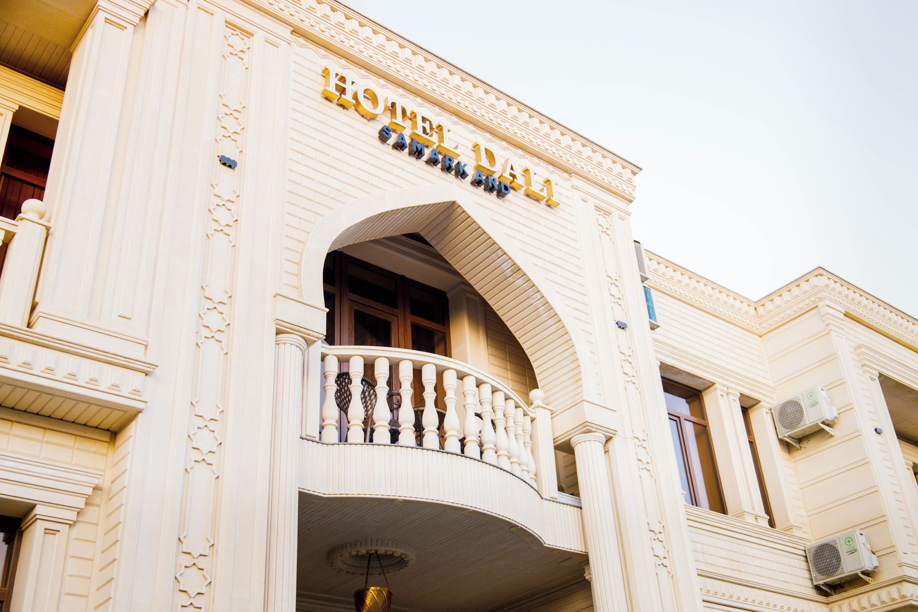 A hotel facade with a prominent arched entrance and a balcony with balustrades.