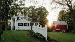 A white house with a red barn, surrounded by a white picket fence and trees. - Historic LaMothe Landing & Farmhouse|SPAC|Track| (Greenfield Center)