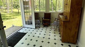 A room with a large wooden cabinet, a door leading outside, and a view of a grassy yard through windows. - Historic LaMothe Landing & Farmhouse|SPAC|Track| (Greenfield Center)