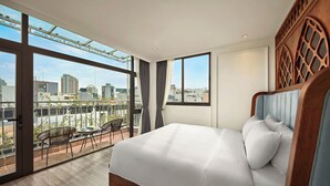 Une chambre d’hôtel moderne avec un grand lit, un balcon avec des chaises et une vue sur la ville.