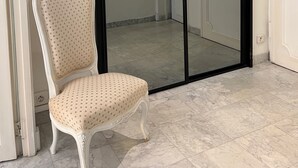 A room with a white chair, a sliding glass door, and a light fixture on the wall.