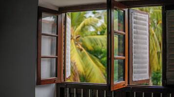 A bay window with multiple panes, a white towel hanging on one of the windows, and a view of green foliage outside.
