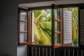A bay window with multiple panes, a white towel hanging on one of the windows, and a view of green foliage outside.