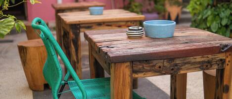 A rustic outdoor seating area with wooden tables and chairs, surrounded by potted plants.