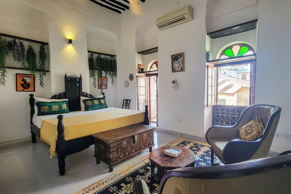 Una habitación con cama, una silla, una mesita y un ventanal con vistas.
