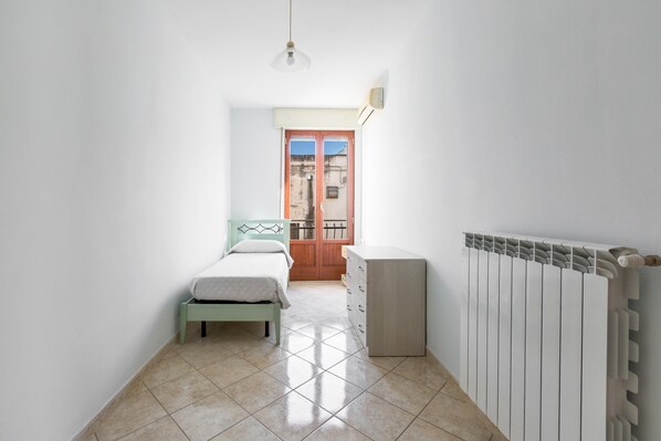 A narrow room with a bed, a radiator, and a door leading to an outdoor area. - 3829 Casa Milena by Barbarhouse (Manduria)