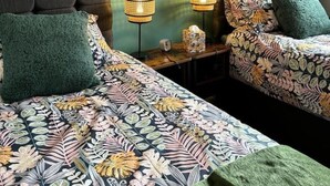 Une chambre d’hôtel avec deux lits, un mur vert et des œuvres d’art encadrées.