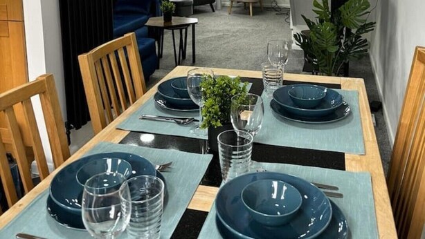 Un coin repas avec une table dressée pour quatre personnes, un canapé et une table basse en arrière-plan.